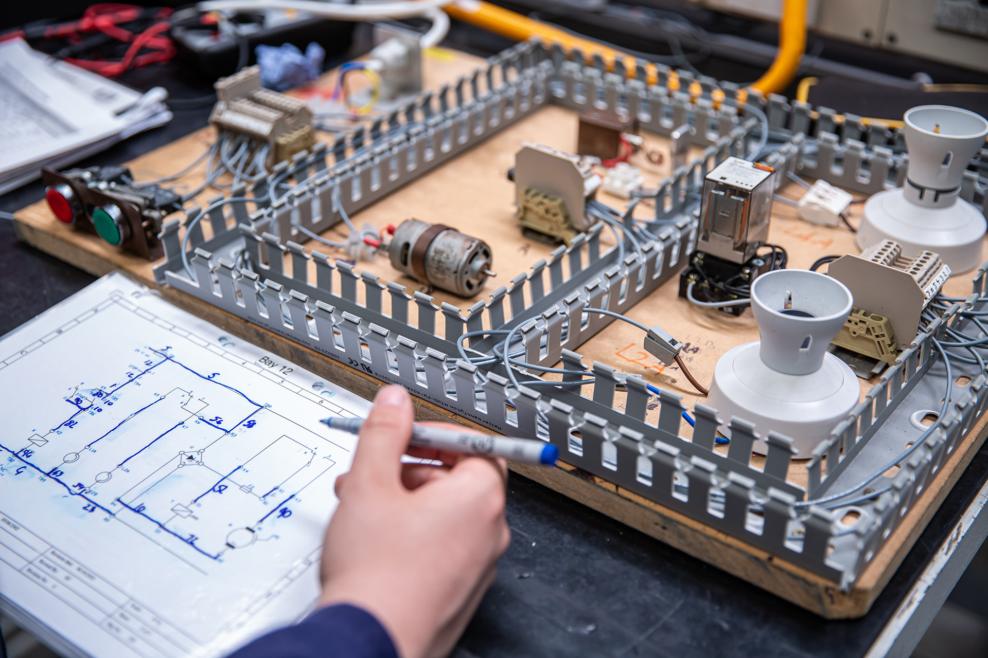 A trainee drawing an electrical wiring diagram