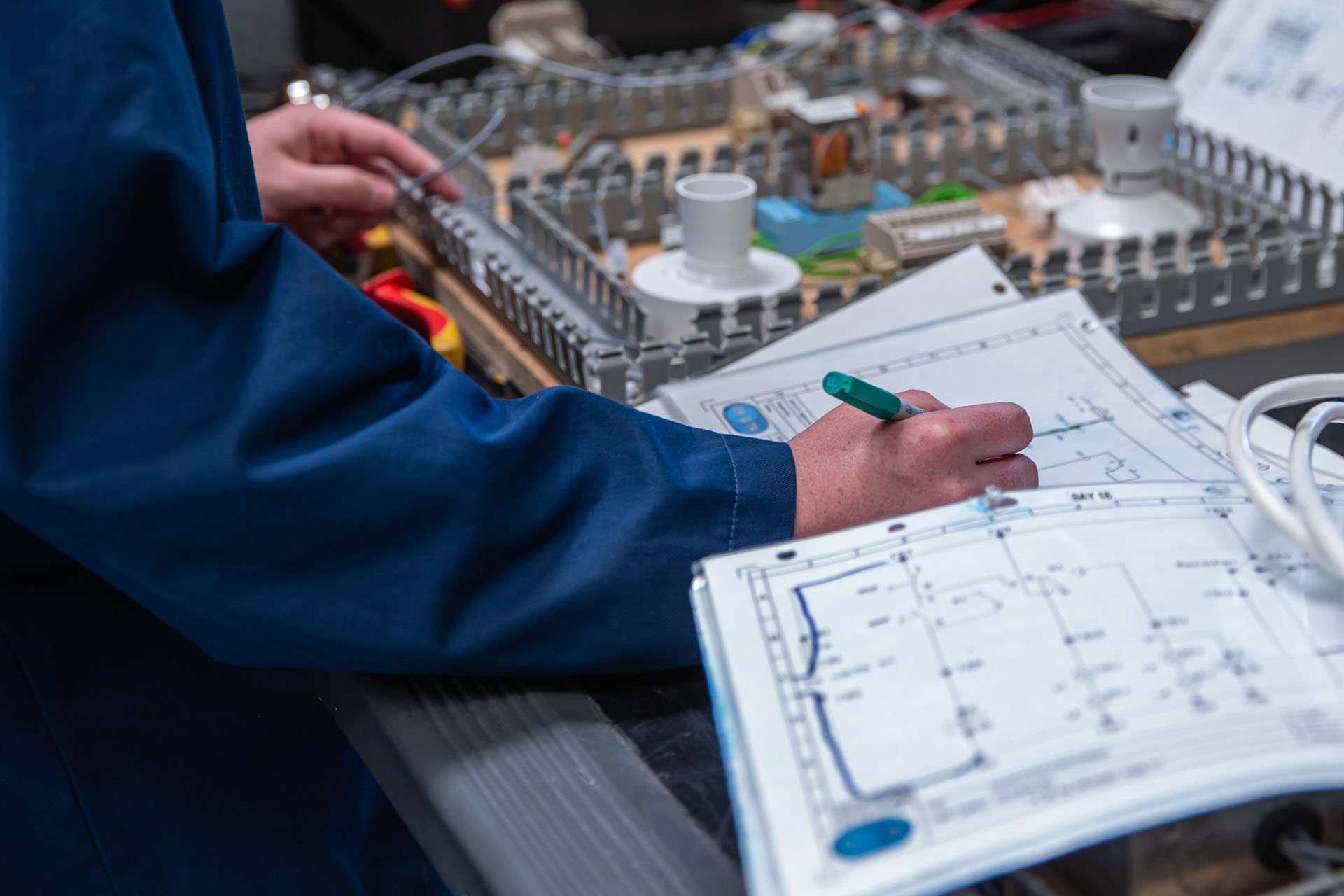 Engineering trainee reviewing diagram beside training rig