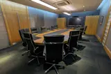 Executive boardroom with large oval wooden table and black leather chairs