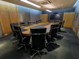 Executive boardroom with large oval wooden table and black leather chairs